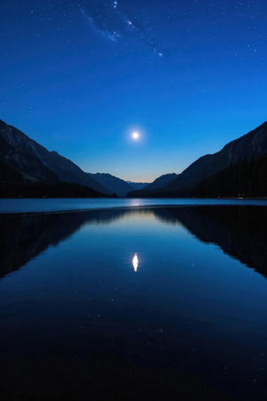 Moonlight reflected in the calm surface of a mountain lake at nightの素材