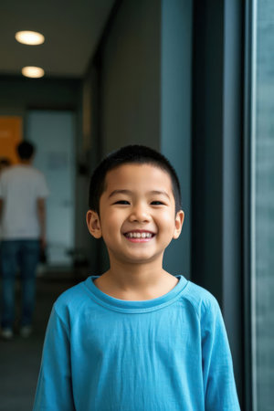 Portrait of smiling little boy standing in corridor of school or kindergartenの素材