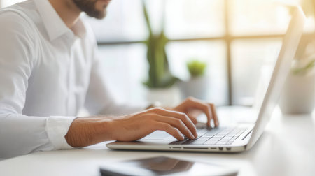 Close-up of male hands typing on laptop keyboard while sitting at table in officeの素材