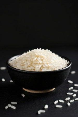 Raw rice in a bowl on a black background. Selective focus.の素材