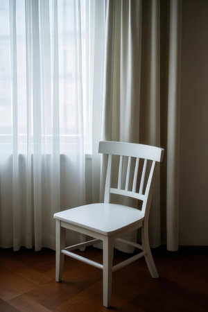 White chair in a room with a window and curtains in the backgroundの素材