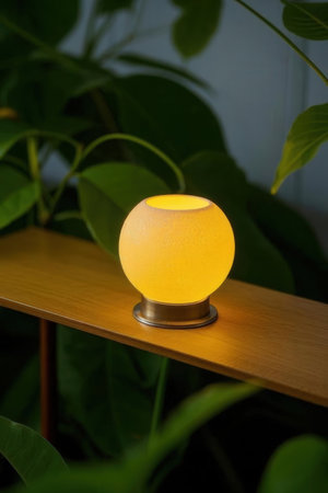 Candle holder on a wooden shelf in a room with green plantsの素材