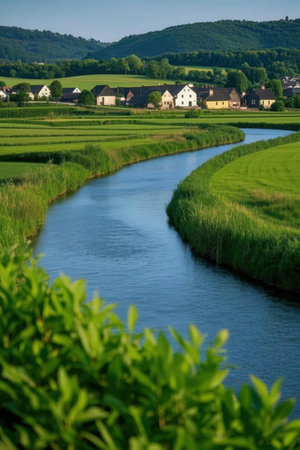 A small river flowing through a village in the middle of a green fieldの素材