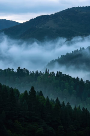 Mountain landscape with foggy forest and church in the foreground.の素材