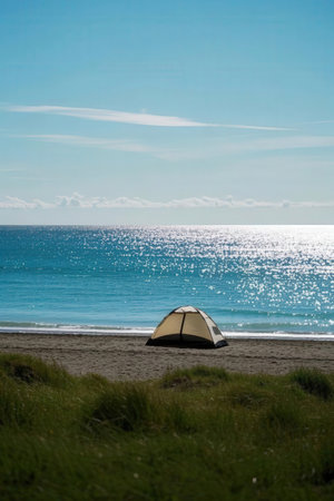 Camping tent on the beach with blue sea and sky in backgroundの素材