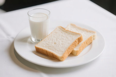 Sliced bread and glass of milk on white table, stock photoの素材