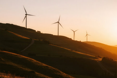 Wind turbines on a hillside in the rays of the setting sunの素材