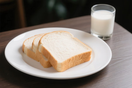 Sliced bread on white plate with a glass of milk.の素材