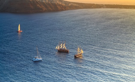 sailing in the Aegean Sea off the coast of Santorini at sunsetの写真素材