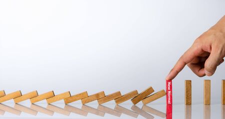 Businessman hand stopping falling wooden dominoes effect from continuous toppled or risk. Economic crisis. Risk Management concept.New normal concept.の写真素材