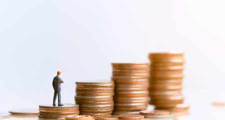 Miniature people: Businessman standing on coin stack.  Plan investment strategies and goals....