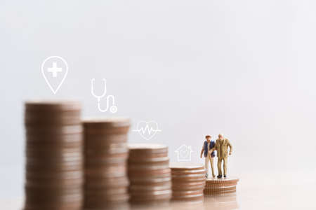 Miniature people: Elderly people sitting on coins stack. social security income and pensions. Money saving and Investment. Time counting down for retirement concept.の写真素材