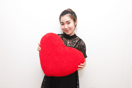 Beautiful woman is hold heart pillow and smiling look like happy, In love concept.の写真素材