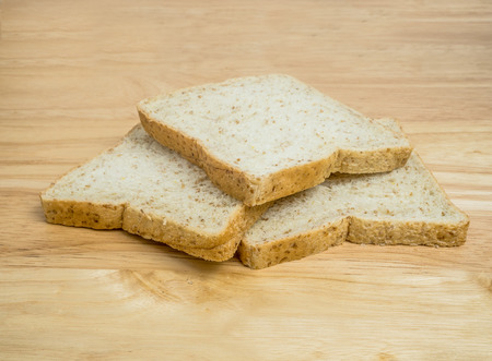 Three slice whole wheat bread stacked on wooden tableの写真素材