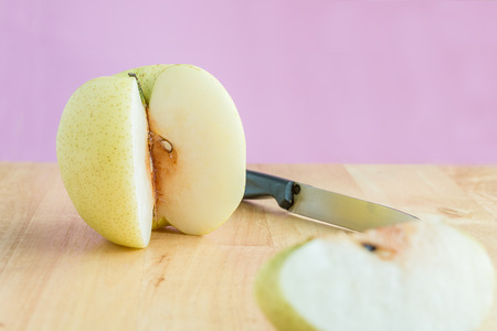 Peel chinese pear by knife on the wooden boardの写真素材