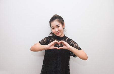 Asian woman making a heart sign with her hands, body languageの写真素材