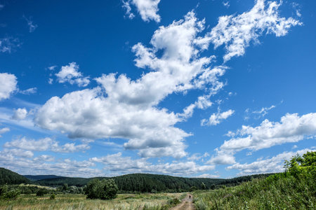 The person leaves afar on the road with big cloudsの写真素材