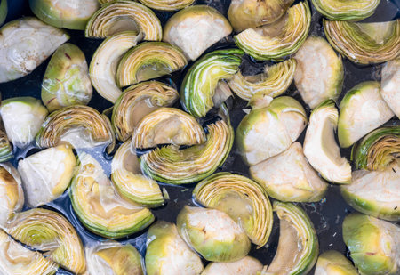 Cut artichokes in water on market stall. Green healthy vegetables.の写真素材