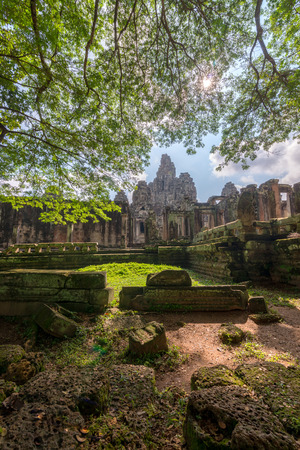 View of Bayon temple with rocks and tree branches foreground at Siem Reap, Cambodia.の写真素材