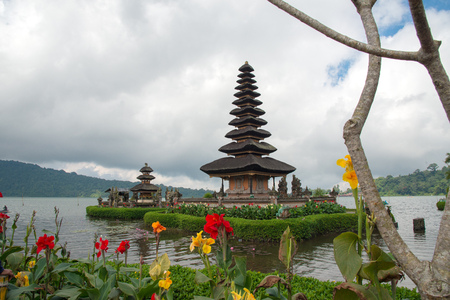 Pura Ulun Danu temple on a lake Beratan on cloudy day with green grass and colorful flowers foreground at Bali, Indonesia.の写真素材