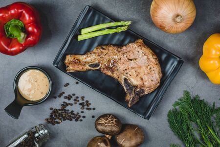 Top view of grilled pork steak surrounded by organic vegetable ingredients.の写真素材