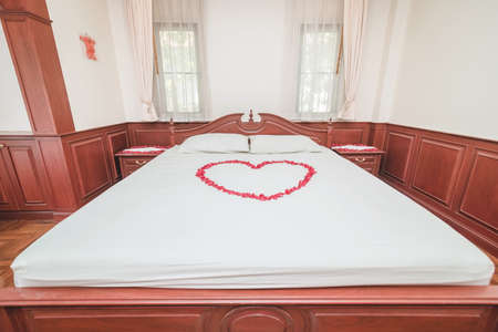 A bed decorated with heart-shaped rose petals at a wedding ceremony in Thailand.の写真素材