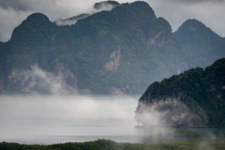 The scenery of the archipelago of the Sametnangshe island in the morning with the mist and fog over the summit in Phang Nga province, Thailand.の写真素材