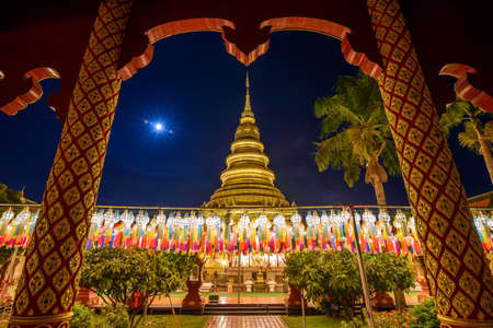 The scenery of Wat Phra That Hariphunchai at dusk on Loy Krathong Festival that decorated with colorful lamps in Lamphun province, Thailand. (The Thai texts in this pic are the prayers)の写真素材