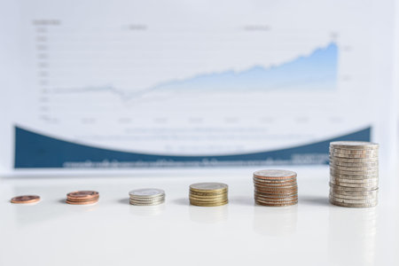 The stacks of Thai baht coins with the increasing trend with blue charts background. Money and financial concepts.の写真素材