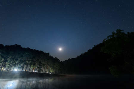 The scenery of the Pine forest with the moon on the reservoir at dawn in Pang Oung, Mae Hong Son, Thailand.の写真素材