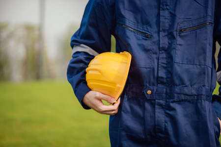 Close-up view of engineering male construction worker holding safety yellow helmet.の写真素材