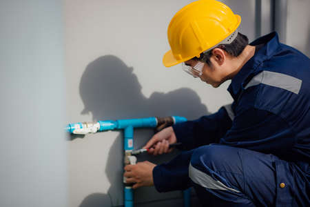 A plumber is fixing the leaked pipe outdoors.の写真素材