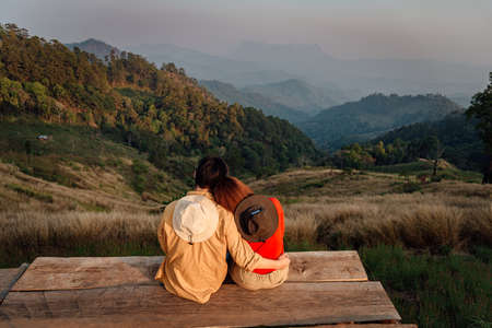 Rear View of a sweet couple sitting and looking at a beautiful view at Hadubi viewpoint, Chiang Mai, Thailand.の写真素材