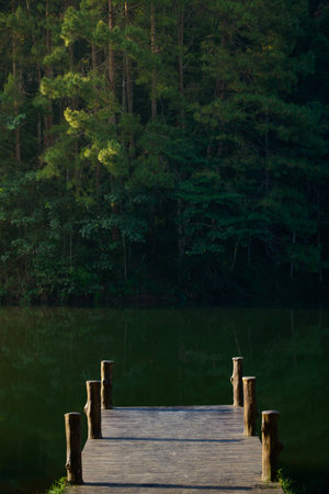 A tranquil scene of the wooden bridge juts into the reservoir at Pang Oung, Mae Hong Son, Thailand.の写真素材