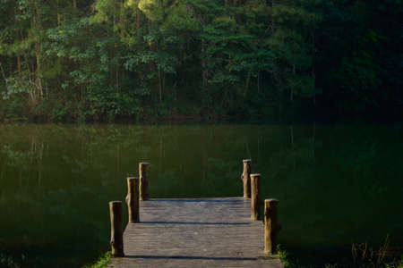 A tranquil scene of the wooden bridge juts into the reservoir at Pang Oung, Mae Hong Son, Thailand.の写真素材