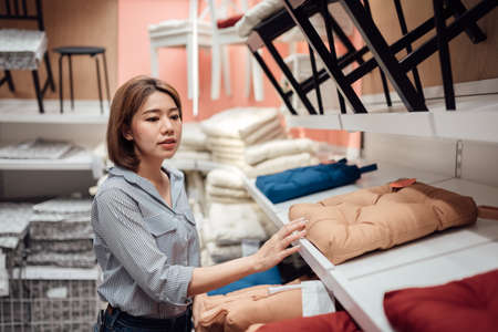 An Asian woman is selecting a seat cushion at the mall.の写真素材