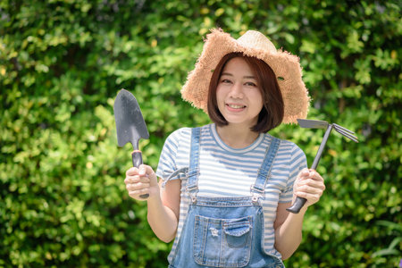 An Asian woman gardener is holding garden equipment tools.の写真素材