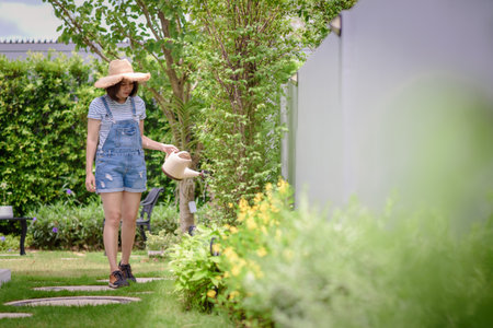 An Asian woman is watering plants in the garden.の写真素材