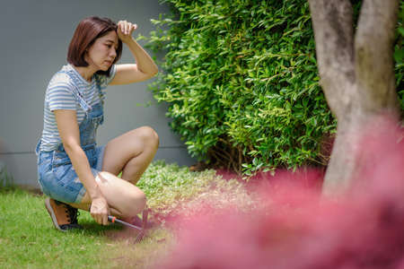 An Asian woman gardener is tired and takes a short break during gardening.の写真素材