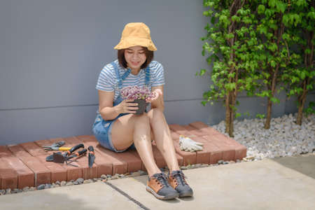 An Asian woman gardener is happy and proud of her planting flowers.の写真素材