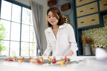 An Asian woman playing soccer (football) table board game. Leisure activity and sports entertainment conceptsの写真素材