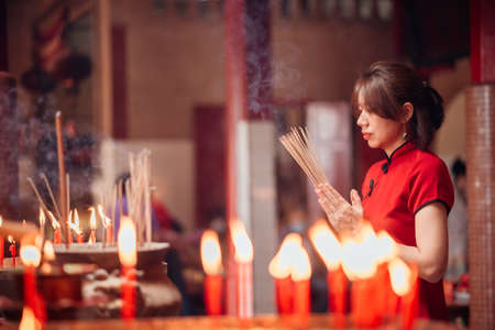 An Asian woman lighting incense sticks to pay homage to the Chinese New Year.の写真素材