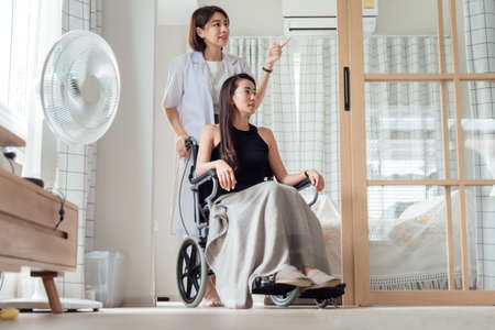 A female doctor or nurse is looking after a patient in a wheelchair.の販売画像
