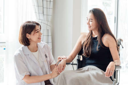 A female doctor or nurse is looking after a patient in a wheelchair.の写真素材