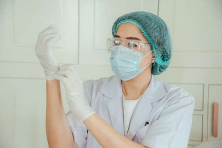 A female doctor is putting on a glove before surgery.の写真素材