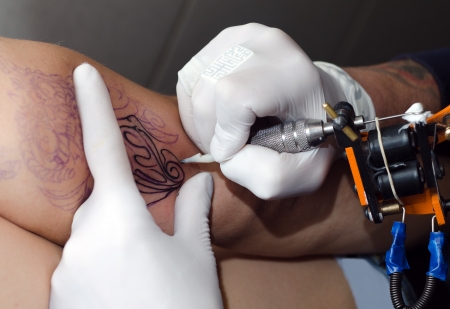 Tattoo artist makes the tattoo on armの写真素材