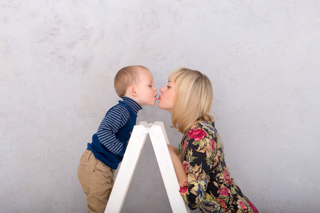 son kissing his mother standing on a sliding ladderの写真素材