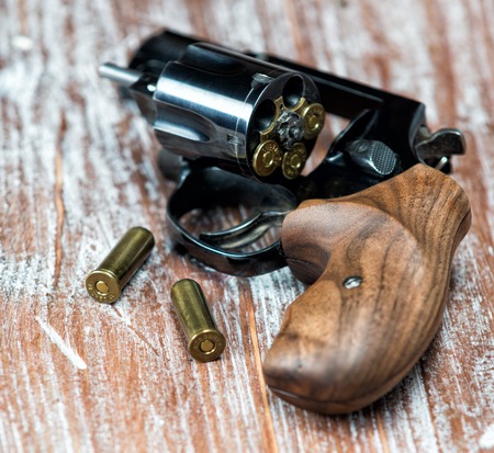small revolver lying on a wooden table, shallow depth of fieldの写真素材