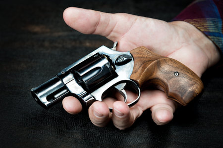 small revolver lies in a man's hand