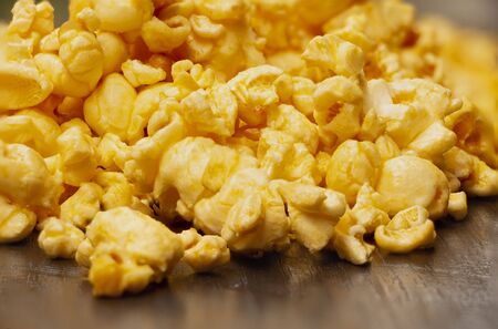 closeup heap of delicious yellow popcorn coated with sweet syrup on a dark brown table.の写真素材